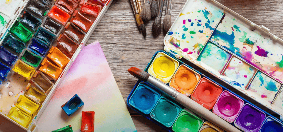 Photo of a paint palette with a variety of colors and different brushes nearby