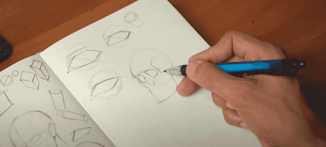 Photo of a hand holding a blue pen, sketching a skull on a notebook