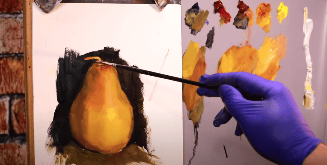 Photo of a hand wearing blue gloves, holding a brush and painting a pear