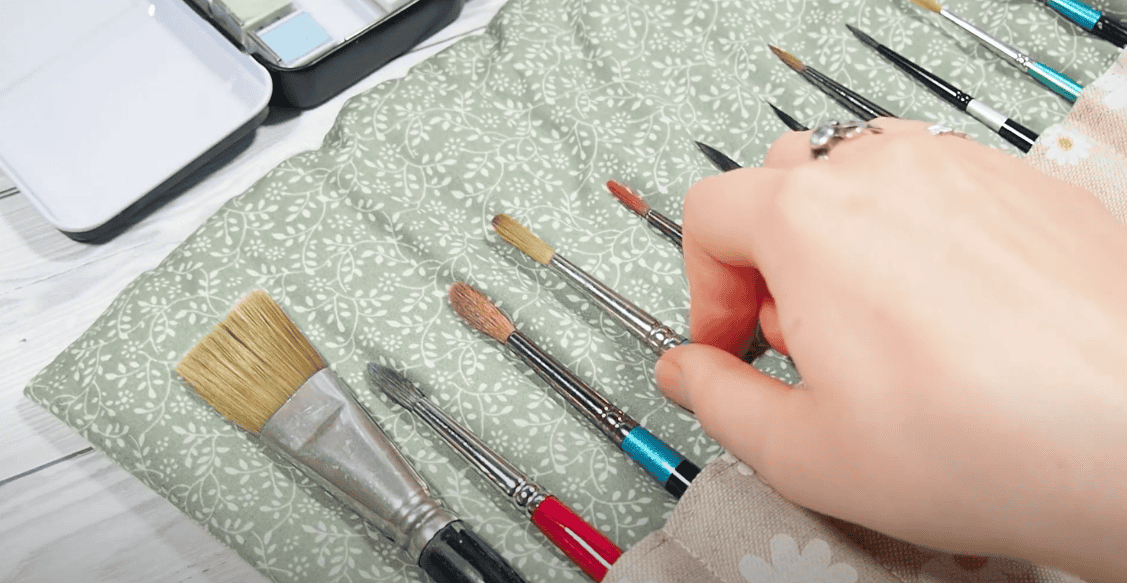 Photo of a hand arranging paint brushes in a paint brush organizer