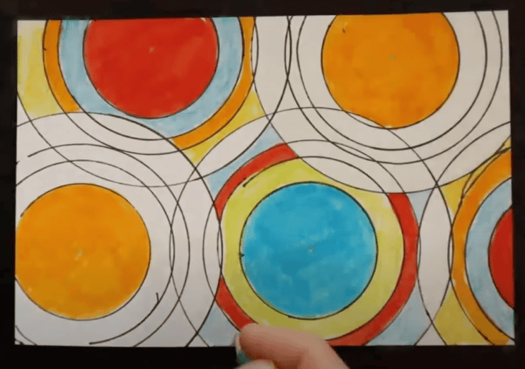 Photo of a hand drawing uniform geometric shapes with vibrant colors